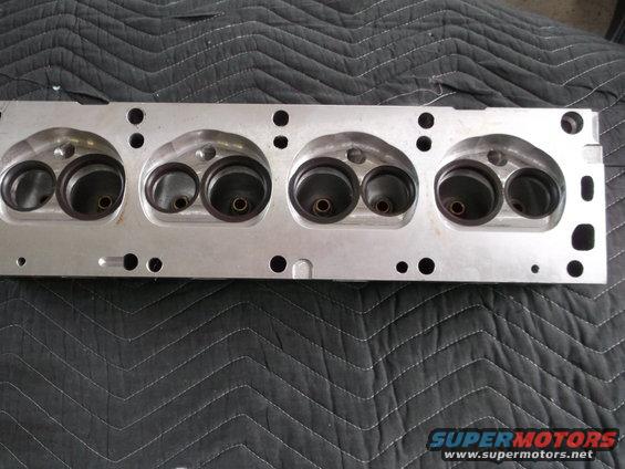 Close-up of an aluminum engine cylinder head with four pairs of intake and exhaust ports
