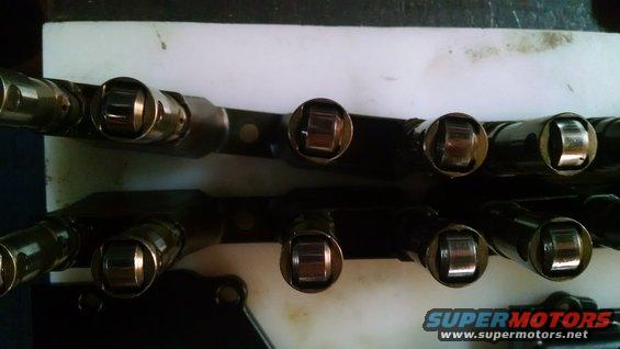 Two rows of engine valve train rocker arms on a workbench