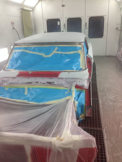 1964 Ford Fairlane in paint booth, masked for repair