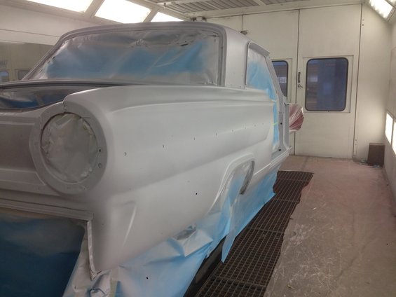 1964 Ford Fairlane in paint booth, covered in primer and masking tape