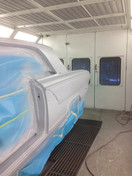 1964 Ford Fairlane side view in paint booth, covered in plastic