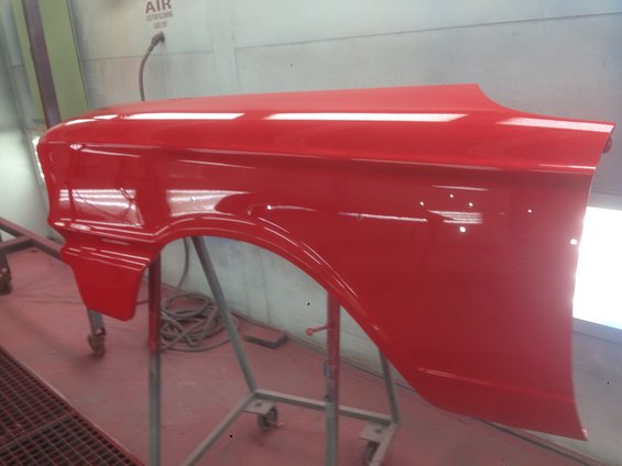 Red car fender on a stand in a paint booth