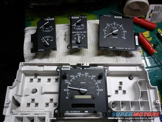 Ford Bronco instrument cluster gauges and housing disassembled. Includes fuel, temp, and tachometer gauges