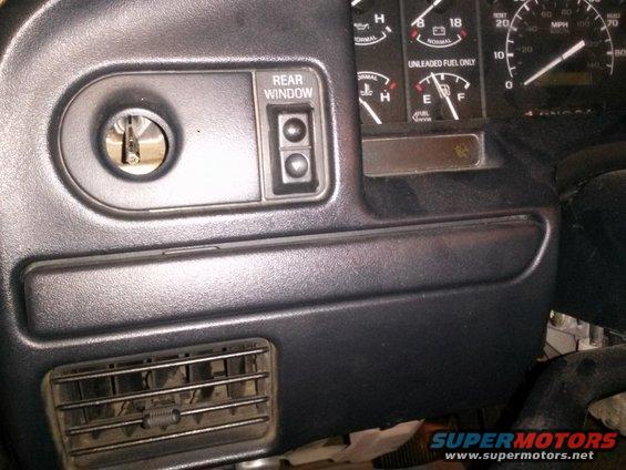 Dashboard with ignition, rear window controls, and gauges. Air vent visible below