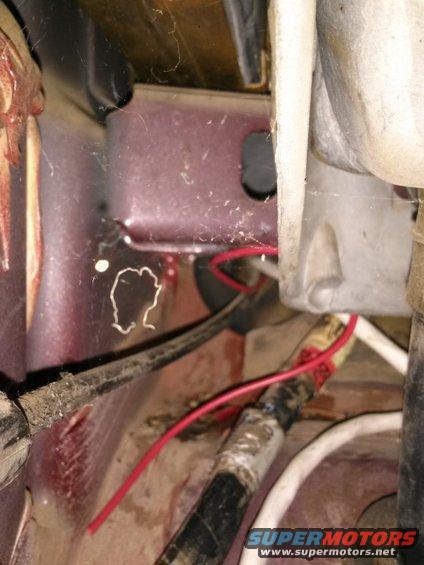 Close-up of red and black wires connected to metal brackets, with cobwebs