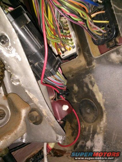 Close-up of a vehicle's interior wiring harness and fuse box with red and multi-colored wires