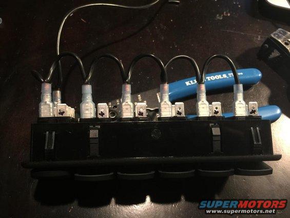 Wiring harness connected to a block of rocker switches, with a blue KLI TOOLS plier in the background