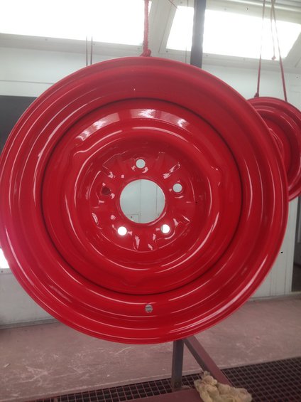 red painted steel wheel rim hanging, another rim visible behind it