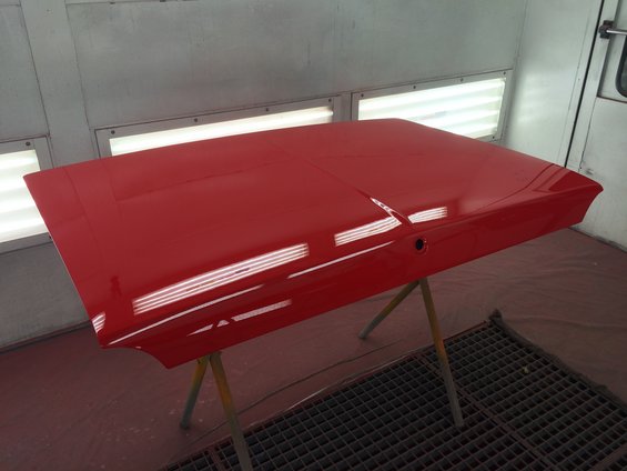 Red car hood on stand in paint booth