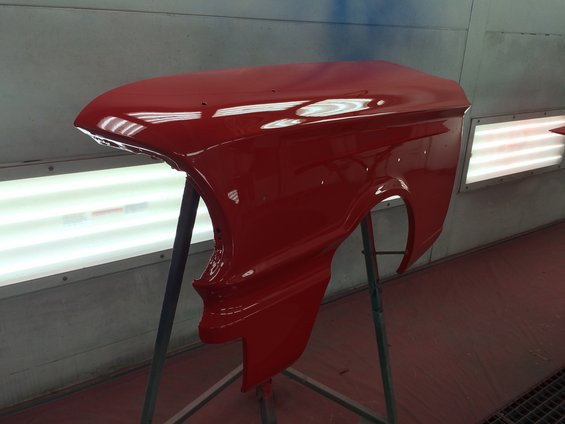 Red car fender on a stand in a paint booth