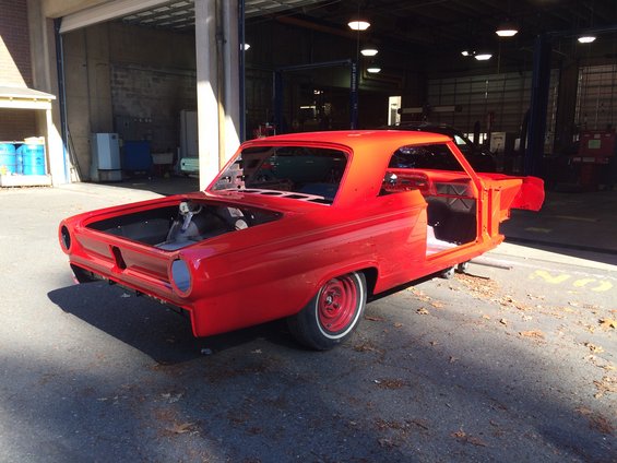 Red 1964 Ford Fairlane body in a garage, stripped down for restoration. Hood and doors are open