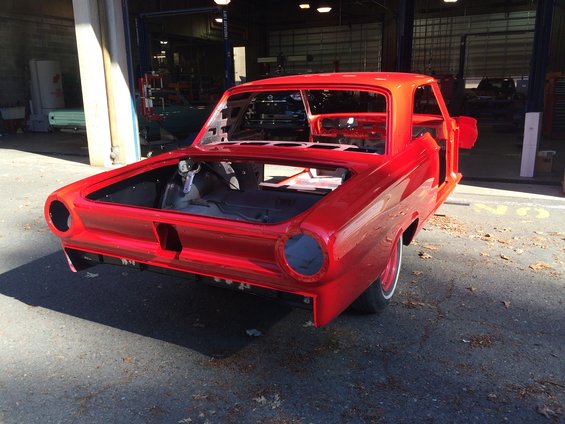 Red 1964 Ford Fairlane body in a workshop, viewed from the rear