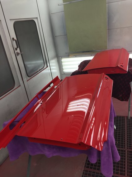 red car doors and hood in a paint booth