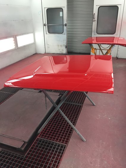 Red car hood on a stand in a paint booth