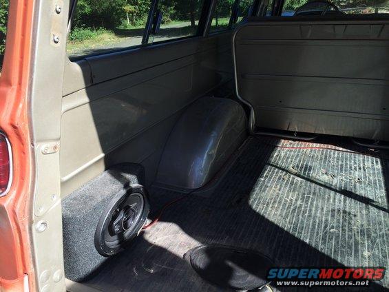 Interior rear cargo area of an old wagon, showing a speaker box and ribbed floor mat