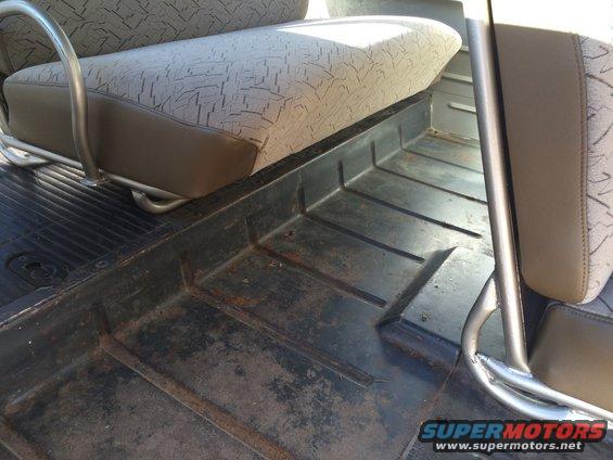 Interior floor of a vehicle showing wear and a portion of a seat with patterned upholstery