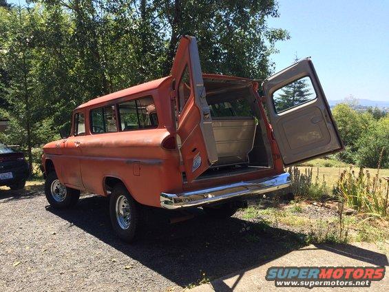 Orange Chevrolet Suburban with rear doors and tailgate open, showing interior