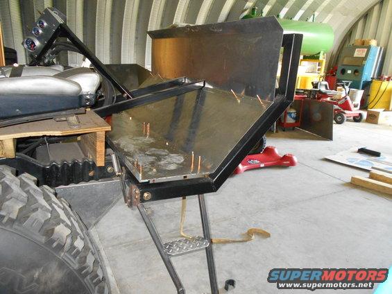 part of a vehicle with custom metal fabrication attached, large tire visible
