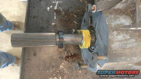 Splined shaft extending from a gray transfer case housing with yellow sealing tape