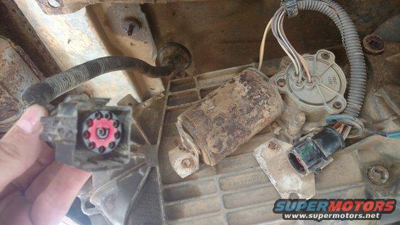 Transfer case electrical connectors with red and gray inserts, one held by a hand