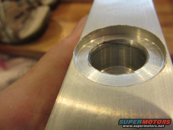 Metal part with a circular recess and machined interior, held by a hand