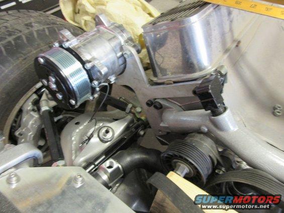 close-up of car engine parts, including a compressor and belts