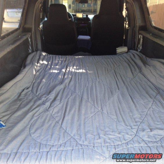 Truck bed interior with a gray and white checkered blanket covering the floor, showing seats and dashboard