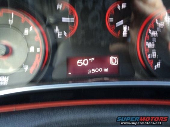 Dashboard gauges with red backlighting and a digital display showing a warning message