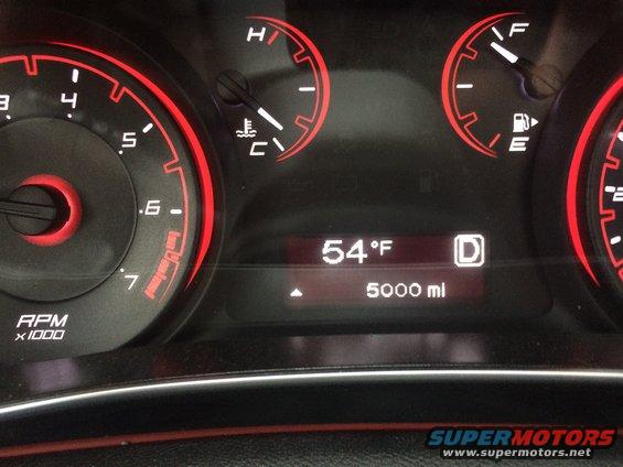 Car dashboard with speedometer, tachometer, and digital display showing 64 degrees
