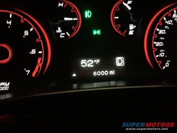 Dashboard gauges showing 52F, 6000 miles, and D for drive. The tachometer reads up to 7000 RPM