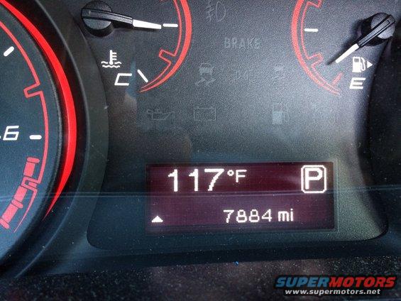 Vehicle dashboard showing 117°F and 7884 miles, with red-trimmed gauges
