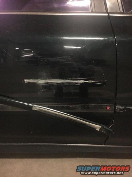 Dark green car door with visible damage and repair attempts
