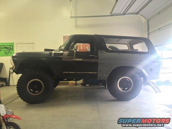 Dark green Ford Bronco with large tires, seen from the side in a garage