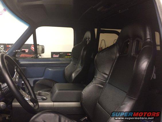Interior view of a vehicle with aftermarket racing seats, custom steering wheel, and center console