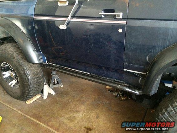 Side view of a 1988 Ford Bronco on jack stands, showing the rock sliders and large tires