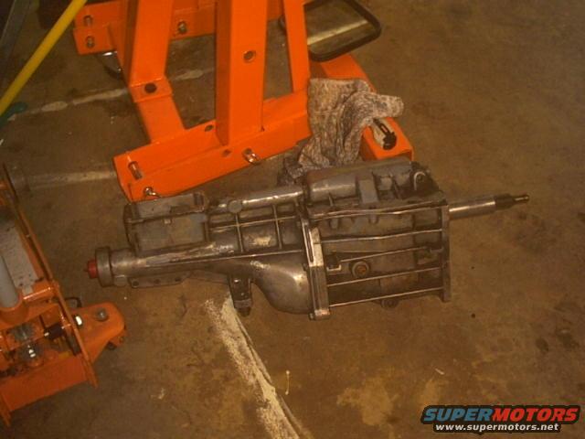 Metal transmission on a concrete floor next to orange jack stands
