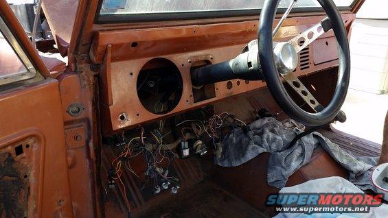 Bare interior of a vintage truck cab with stripped dash and steering wheel
