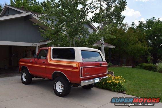 Red 1978 Ford Bronco with a white top and orange/yellow side stripes parked in a driveway
