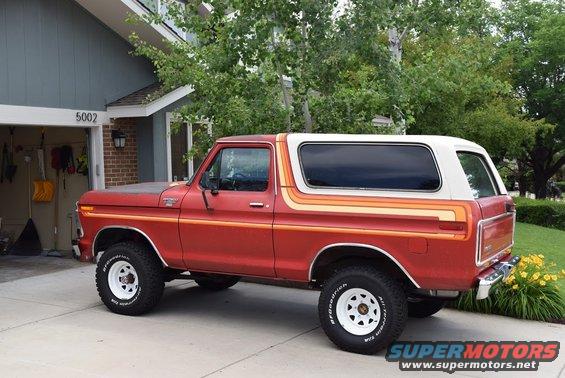 Red 1978 Ford Bronco with white hardtop and colorful side stripes parked in driveway