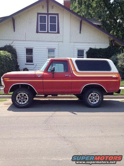Red 1978 Ford Bronco side view with white top and racing stripes
