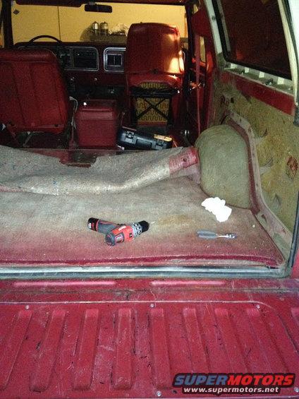 Interior view of a red SUV's cargo area and front seats, with a drill and screwdriver on the floor