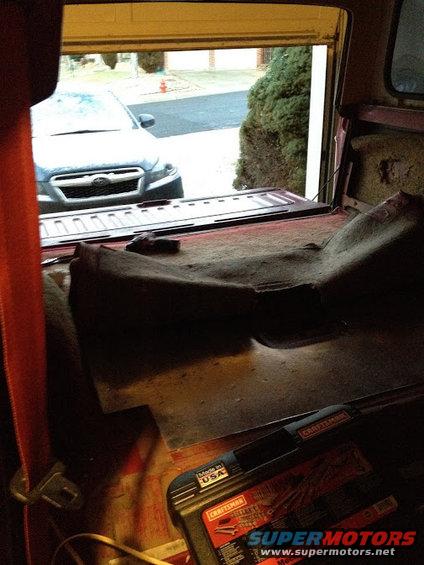 Looking out from inside a vehicle's cargo area at another car parked outside a garage