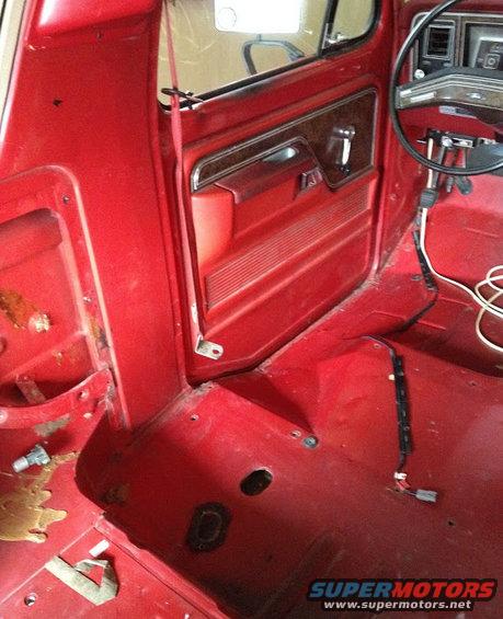 Red interior of a 1978 Ford Bronco, showing door panel and dashboard