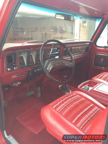 1978 Ford Bronco interior with red seats and wood grain trim on the dashboard