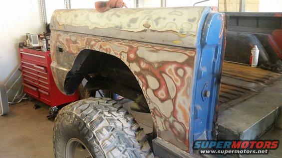 Ford Bronco body with primer and body filler, big off-road tire, in a garage