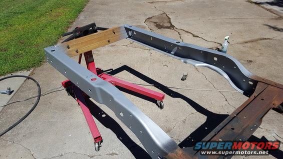 vehicle frame on red stands, partially painted gray