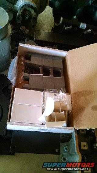 Box of engine parts, some in plastic packaging