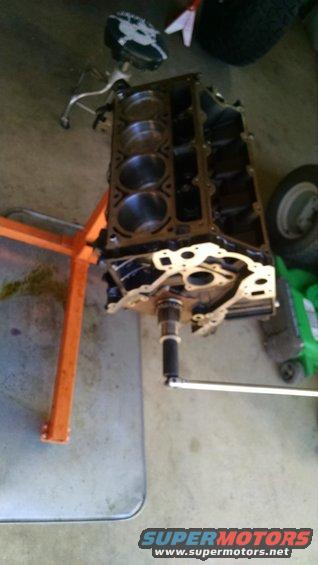 Engine block on an orange engine stand, with a torque wrench attached