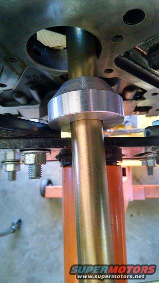 Close-up of a metal shaft passing through a bearing and into a larger component, possibly part of a steering column or suspension