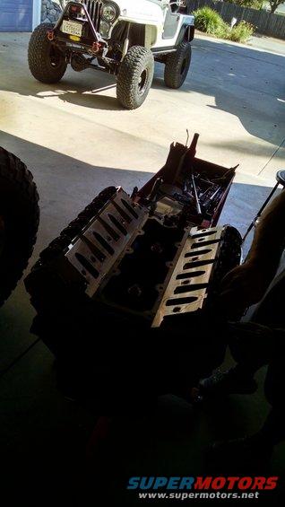 White 1985 Jeep CJ7 with large tires, front view. Engine block in foreground